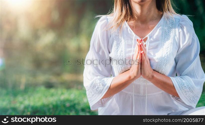 Meditation by the water, hands in prayer position, green background. . Meditation by the Water, Hands in Prayer Position.