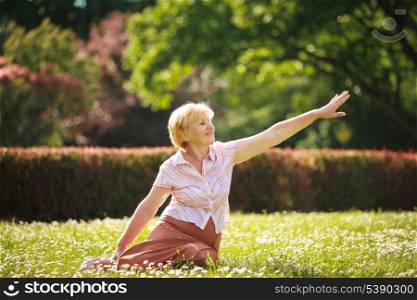 Meditation. Graceful Old Woman in the Park Stretching her Hand