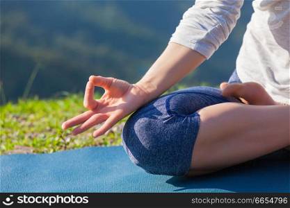 Meditation relaxation concept background - close up of woman in Padmasana yoga lotus pose with chin mudra outdoors with copyspace. Close up Padmasana lotus pose