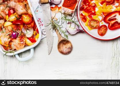 Mediterranean Chicken with colorful vegetables and sweet paprika powder in casserole , preparation on white wooden background with cooking spoon and kitchen knife, top view, border