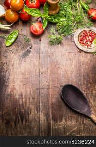 Mediterranean food background. Various fresh seasoning and tomatoes with old cooking spoon on aged wooden background, top view