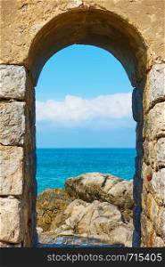 Mediterranean sea and rocky coast through arch in Cefalu, Sicily, Italy