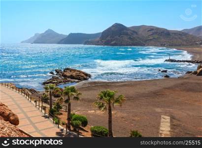 Mediterranean sea summer coastline view with beach, footpath and palm trees (Portman bay, Costa Blanca, Spain).