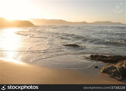 Mediterranean waves washing onto the golden sand at Plage de Petra Muna near Calvi in Corsica