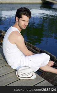 Mediterranean young latin man relaxed on wood pier white hat