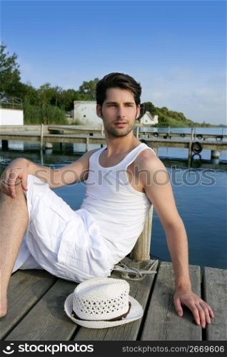 Mediterranean young latin man relaxed on wood pier white hat