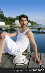 Mediterranean young latin man relaxed on wood pier white hat