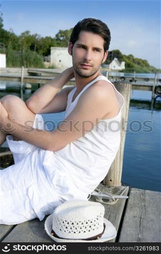 Mediterranean young latin man relaxed on wood pier white hat