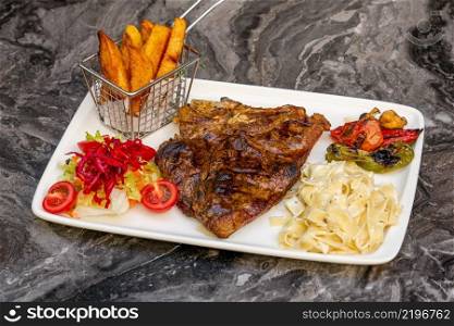 Medium rare Grilled T-Bone Steak with potato wedges, broccoli and wine on serving board block on dark background