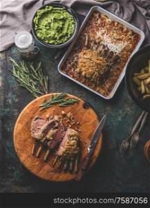 Medium rare roasted lamb racks on wooden cutting board, top view. Meat food