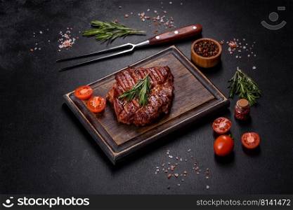 Medium rare sliced grilled striploin beef steak served on wooden board. Grilled ribeye beef steak, herbs and spices on a dark table