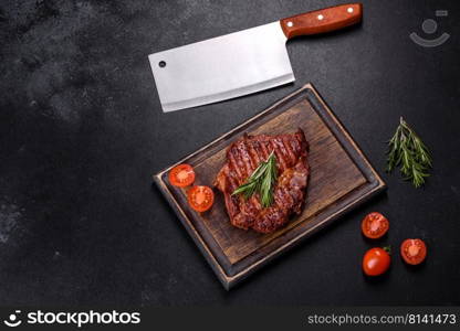 Medium rare sliced grilled striploin beef steak served on wooden board. Grilled ribeye beef steak, herbs and spices on a dark table