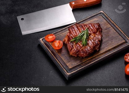 Medium rare sliced grilled striploin beef steak served on wooden board. Grilled ribeye beef steak, herbs and spices on a dark table