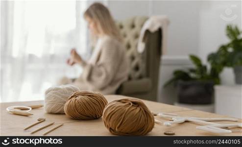 medium shot blurry woman knitting indoors