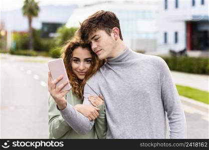 medium shot couple taking selfie outdoors