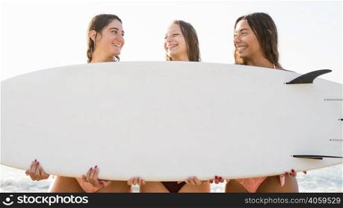 medium shot girl friends holding surf board