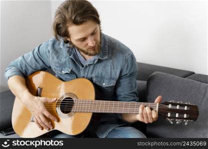 medium shot man playing guitar couch