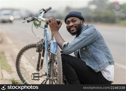 medium shot man posing near bicycle