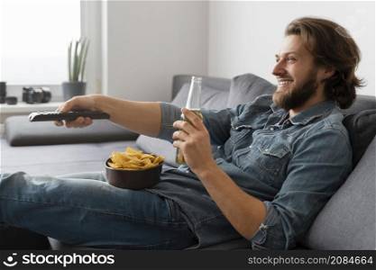 medium shot man with drink watching tv