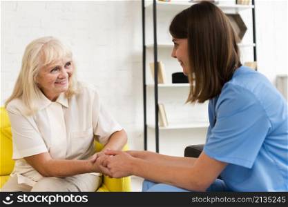 medium shot old woman nurse holding hands