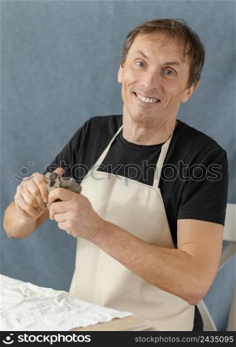 medium shot smiley man holding clay