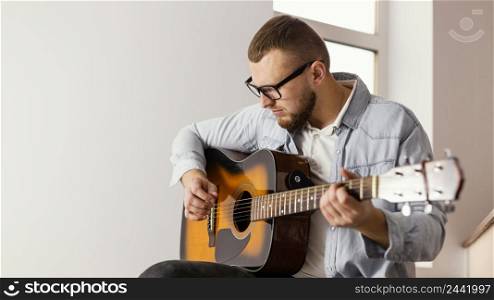 medium shot smiley man playing guitar indoors