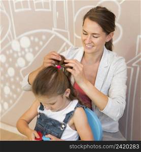 medium shot smiley teacher tying girl s hair