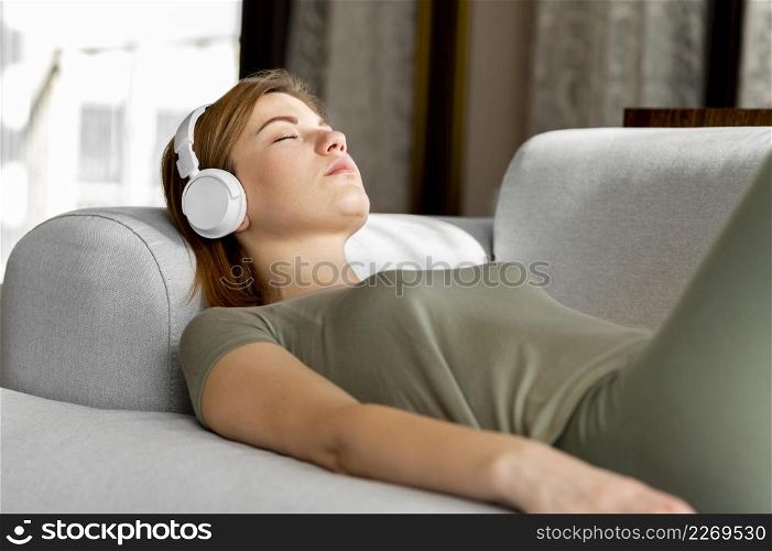medium shot woman couch with headphones