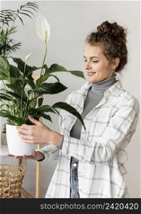 medium shot woman holding plant pot