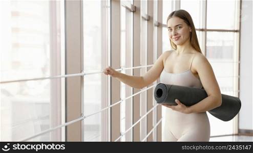 medium shot woman holding yoga mat