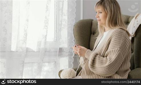 medium shot woman knitting near window