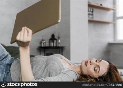 medium shot woman laying with tablet