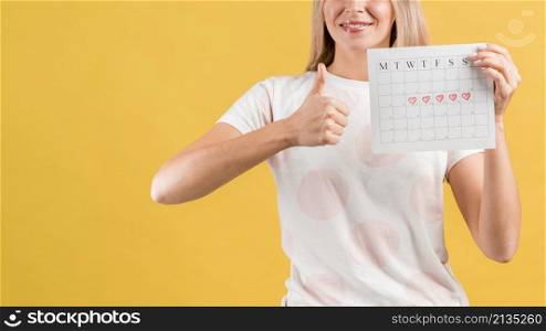 medium shot woman showing her period calendar thumps up