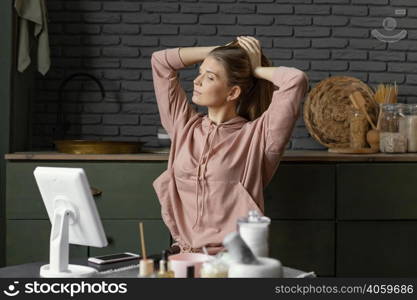 medium shot woman tying her hair indoors