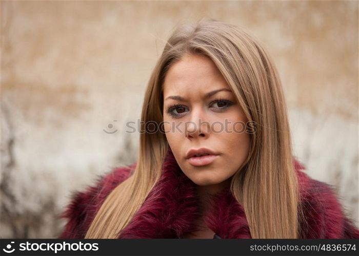 Melancholy young girl with red fur coat looking at camera