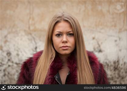 Melancholy young girl with red fur coat looking at camera