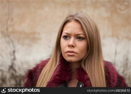 Melancholy young girl with red fur coat looking at side