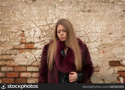 Melancholy young girl with red fur coat looking down