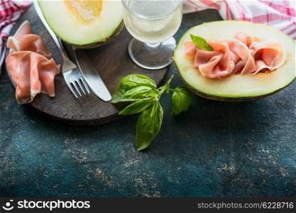 Melon with Prosciutto of Parma ham on dark rustic kitchen table, place for text. Italian food concept