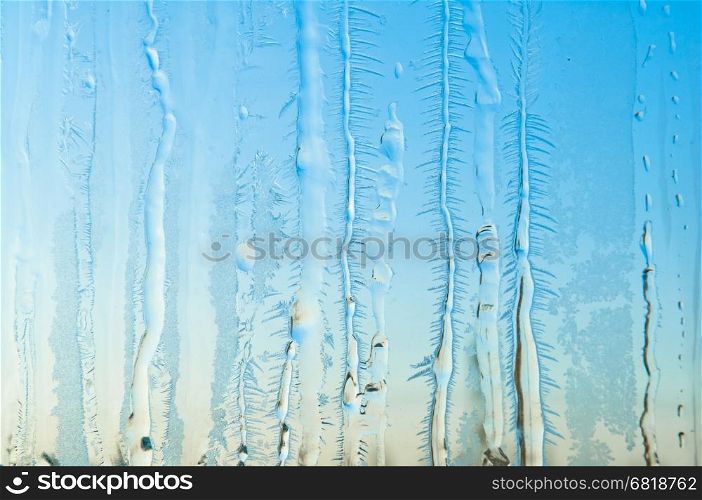 Melted and frosted ice pattern on frosty window glass in winter