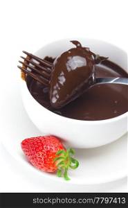 melted chocolate in a cup, fork and strawberries isolated on white
