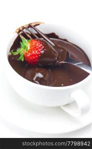 melted chocolate in a cup, fork and strawberries isolated on white