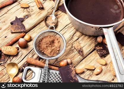 Melting chocolate in a metal bowl. bowl with melted hot chocolate, cocoa beans, nuts and spices