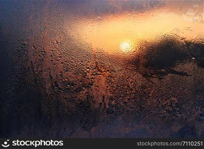 Melting ice, water drops and sunlight on a window pane on a winter morning, close-up natural texture