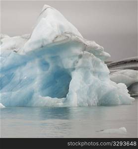Melting iceberg in glacial lake, with an ice cave