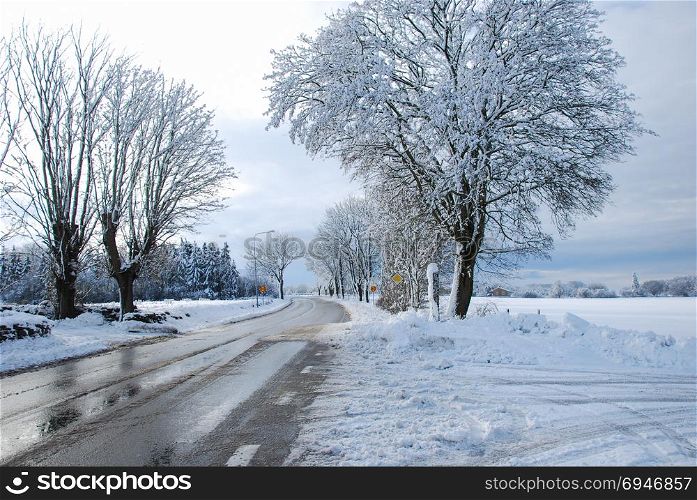 Melting snow and ice on a country road through a wintry landscape