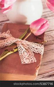 Memo still life with book, key, vintage lace and pink tulips