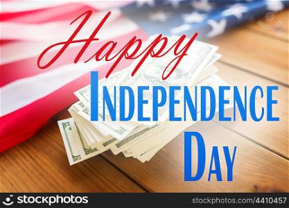 memorial day, patriotism and holiday concept - happy independence day words over american flag and dollar cash money background