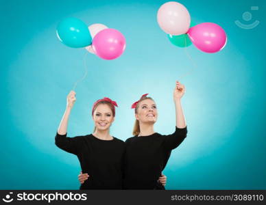Memory of childhood and forgotten dreams. Two cute lovely retro styled women behave like little girls. Adults trying to fly away by balloons to dream come true.. Women like a little girls want fly away by balloons.