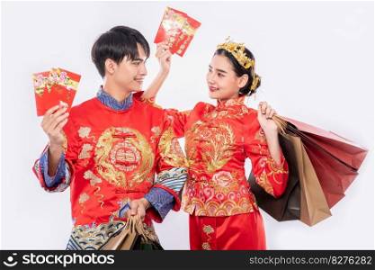 Men and women carry paper bags to go shopping with red envelope